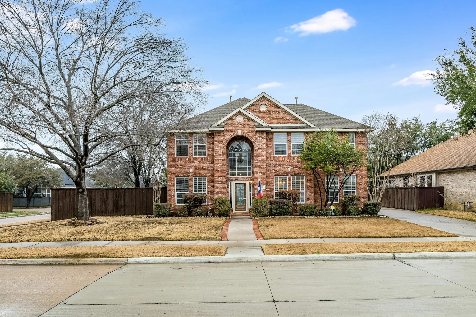 Two-story brick home in Grand Prairie, Texas, under a clear blue sky